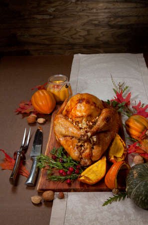 Garnished traditional roasted turkey for Thanksgiving, garnished with roasted winter squash, cranberry, nuts, and fresh herbs. Decoraded with pumpkins, candels, and flowers.の写真素材