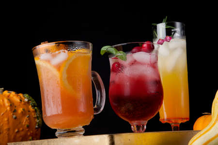 Closeup of Spicy Apple Cider, Pear Sparkler, and Whiskey-Cranberry cocktails on a tray with mini pumpkins. Fall Drinks series.の写真素材