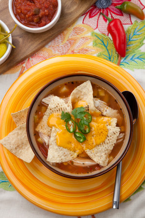 Closeup of a bowl of hot delicious spicy chicken nacho soup, garnished with melted cheese, jalapeno pepper, and fresh cilantro.の写真素材