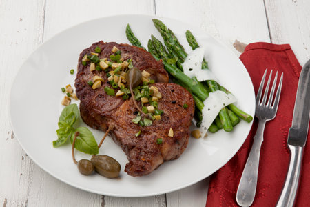 Grilled steak dressed with olive tapenade garnished with asparagus and cheese.の写真素材