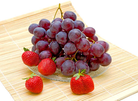 ripe and fresh grapes and strawberries on a white backgroundの写真素材