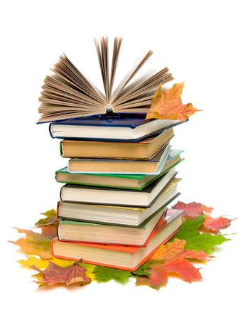 open book on a pile of books and autumn maple leaves closeup on white backgroundの写真素材