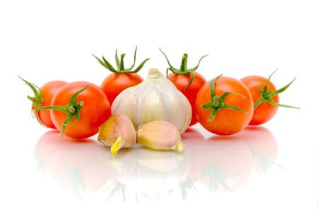 Vegetables. Ripe cherry tomatoes and garlic on a white background close-up reflection.の写真素材