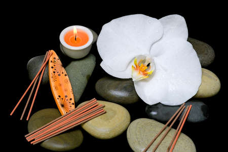 spa composition on a black background. orchid, sea stones, candle and incense sticks.の写真素材