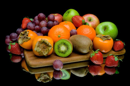 still life of fresh fruit and berries on a black background with reflectionの写真素材