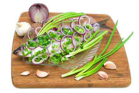 salted herring with onion and garlic on a cutting board isolated on white backgroundの写真素材