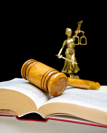 gavel on law book on a black background, the statue of Justice in the background out of focus....