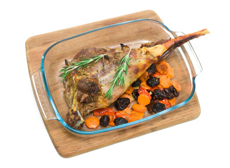 roasted leg of lamb with prunes, carrots and rosemary isolated on white 