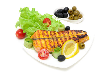 appetizing piece of baked salmon with lemon and vegetables on the plate on a white background. horizontal photo.の写真素材