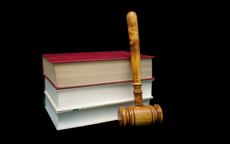 books and a wooden judge's gavel on a black background. horizontal photo.
