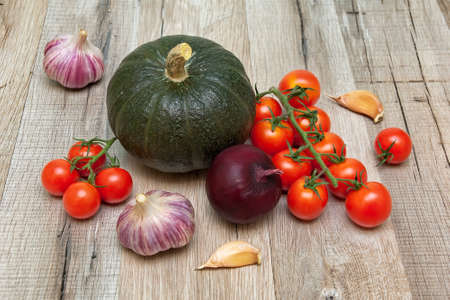 pumpkins, tomatoes, onion and garlic on a wooden background. horizontal photo.の写真素材