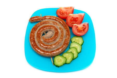Fried sausages with vegetables on a plate. White background - horizontal photo.の写真素材