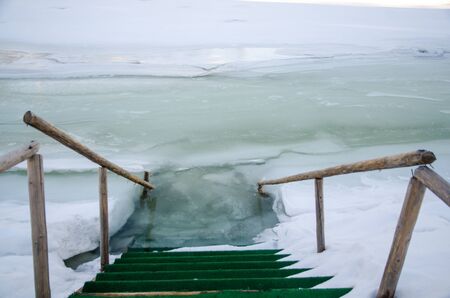 Ladder in hole ice water wooden railingの写真素材