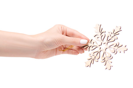 Christmas decoration wooden snowflake on a Christmas tree in hand on a white background isolationの写真素材