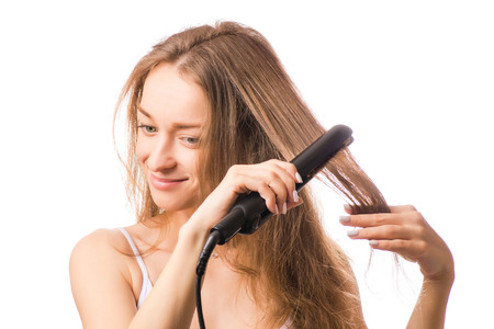 Beautiful young woman hair ironing  on white background isolationの写真素材