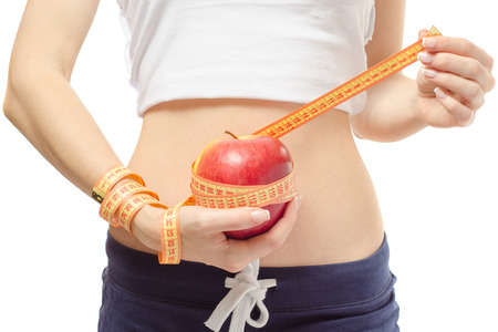 A woman holding an apple wrapped by a measuring tape isolated on white backgroundの写真素材