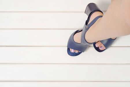 Female feet with blue shoes sandals on a white wooden backgroundの写真素材