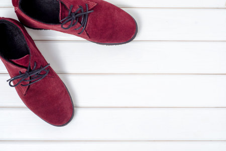 Bordeaux suede female shoes on a white wooden background