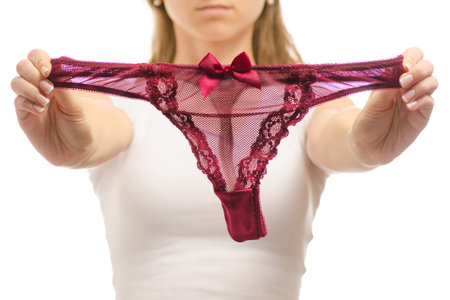 Young woman holds red thong panties on white background isolationの写真素材