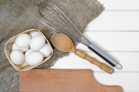 Eggs white wooden spoon whisk on a white wooden backgroundの写真素材