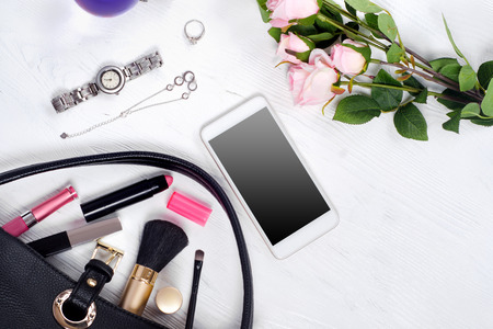 Flowers perfume watch bracelet mobile phone handbag cosmetics on a white wooden backgroundの写真素材