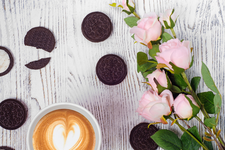 Cup of coffee biscuits flowers on a white wooden backgroundの写真素材
