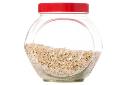 Capacity with a lid of flakes of oats on a white background isolationの写真素材