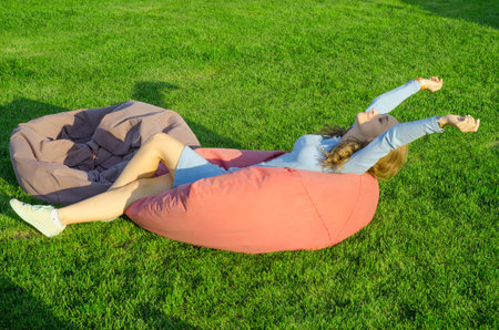 Beautiful young girl in a dress sitting on a bag chair natureの写真素材