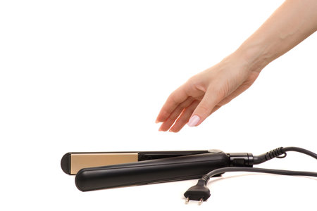 Hair iron in female hand on white background isolationの写真素材