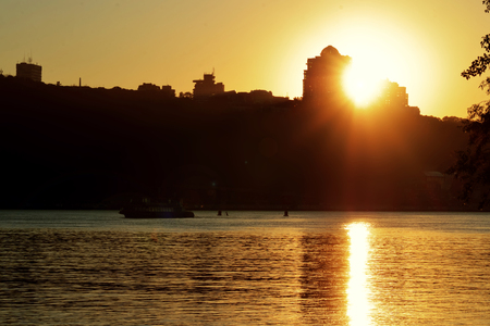 Sunset behind the building above the river with a boatの写真素材