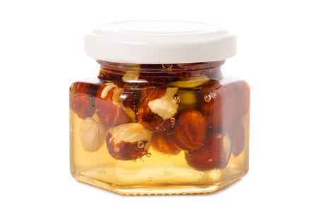 A honey jar with nuts on a white background isolationの写真素材