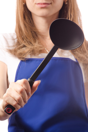 Young woman in apron holding kitchen scoop on white background isolationの写真素材
