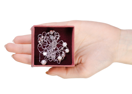 Silver bracelet and chain with pearls in a box of a hand on a white background isolation, top viewの写真素材