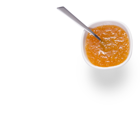 Orange jam in a white bowl with a teaspoon on a white background isolationの写真素材