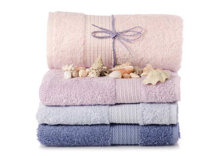 A stack of towels pink blue spa sea seashell stones on a white background isolationの写真素材