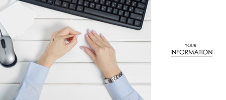 A female hands holding a pencil with a keyboard and a mouse on a wooden white backgroundの写真素材