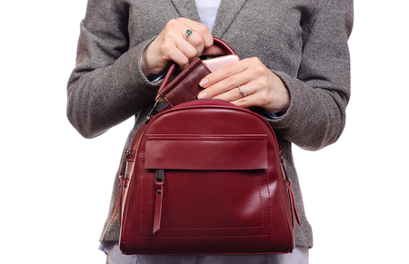 Woman in shirt and jacket put a mobile phone and purse in handbag business on a white background isolatedの写真素材