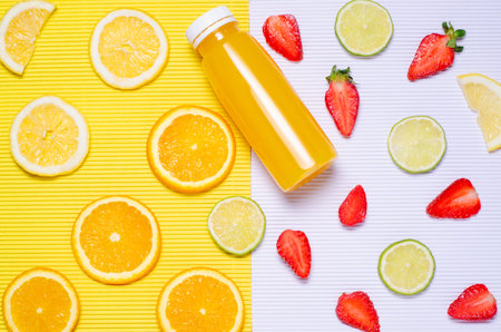 Orange lemon lime strawberry bottle juice  on colorful yellow white background