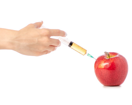 Syringe in the hands of an apple on a white background isolationの写真素材