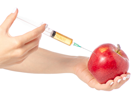 Syringe in the hands of an apple on a white background isolationの写真素材