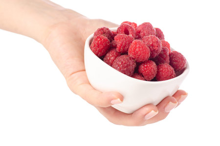 Raspberries in a bowl in hand on a white background isolation