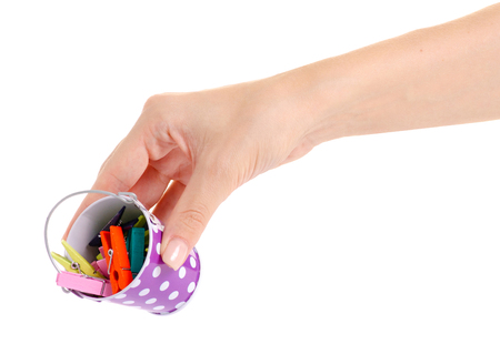 A small bucket with clothespins in hand on a white background isolationの写真素材
