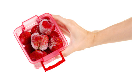Frozen strawberries in a container in hand on a white background isolationの写真素材