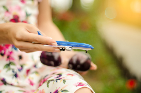 Beautiful woman in dress with airplane in hands summer vacations journey trip blur nature backgroundの写真素材
