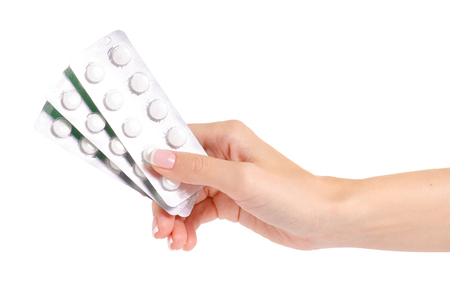 Medicine pills in blister, drug tablets in hand isolated on white background. Pharmacy and medication.の写真素材