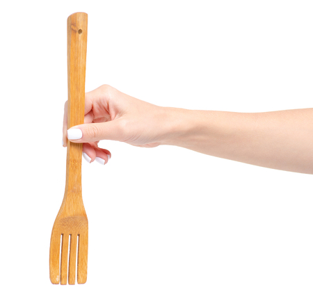 Wooden kitchen fork in a hand on a white background isolationの写真素材