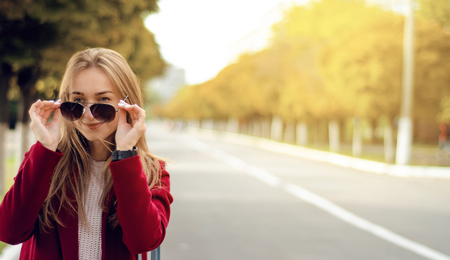 Beautiful woman female bag coat sweater jeans smile watch sunglasses in the street sunの写真素材