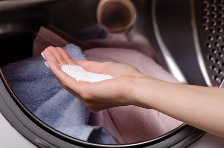 close up of a hand pouring detergent into the washing machine container householdの写真素材