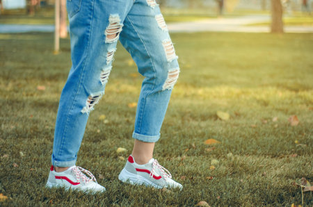 Women's legs jeans sneakers park in the city streetの写真素材