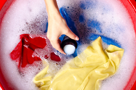 Women washing color clothes in basin enemale powdered detergent liquid laundry gel, top viewの写真素材